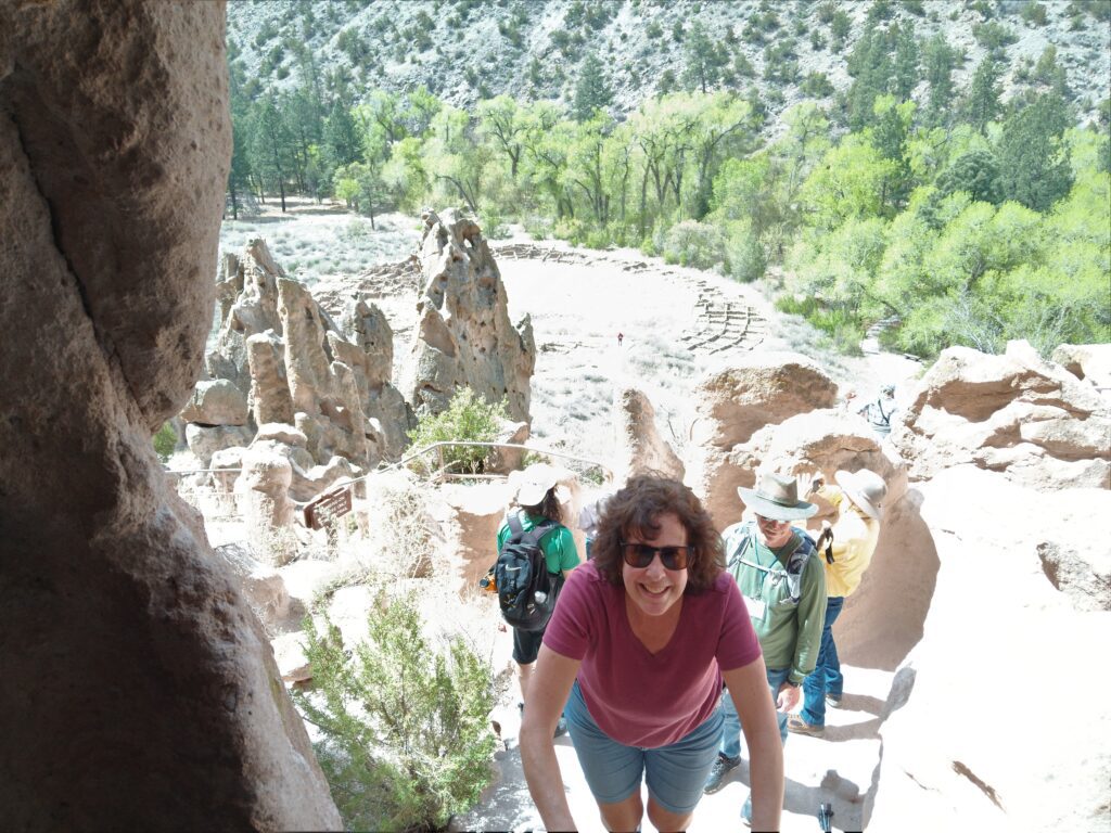 Karen climbing up a ladder to explore a cavate at Bandelier National Monument