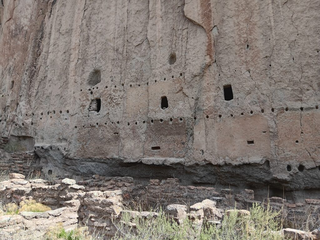 Cliff walls with holes and remains of Long House at Bandelier National Monument